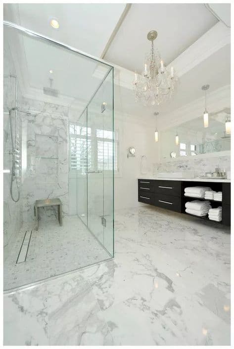 Grand marble bathroom with glass shower and crystal chandelier